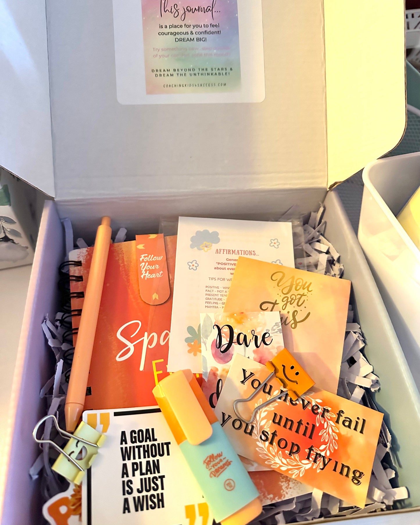 Gift box with motivational items including a pen, cards, and a notebook.