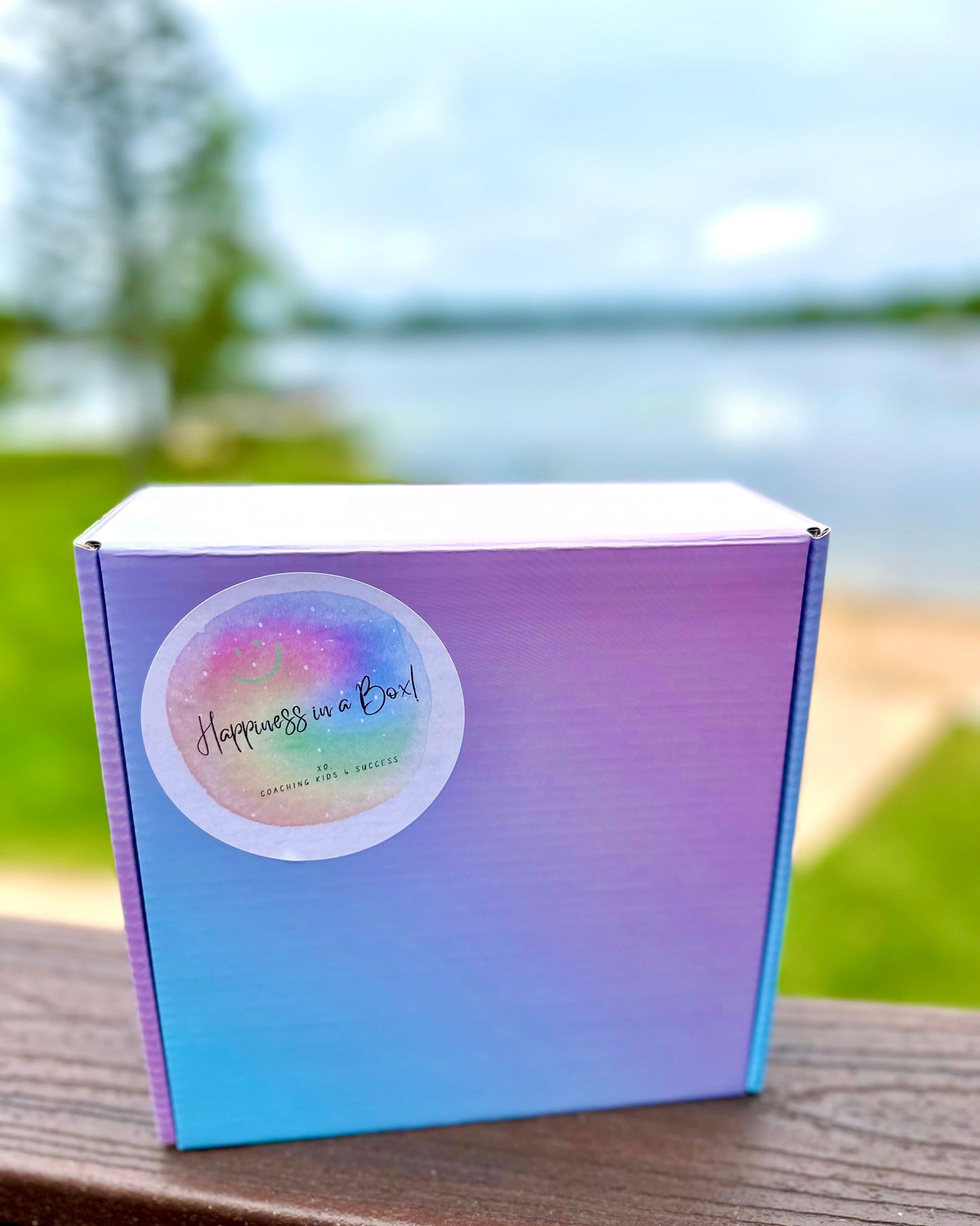 Gradient purple and blue box with 'Happiness in a Box' label outdoors