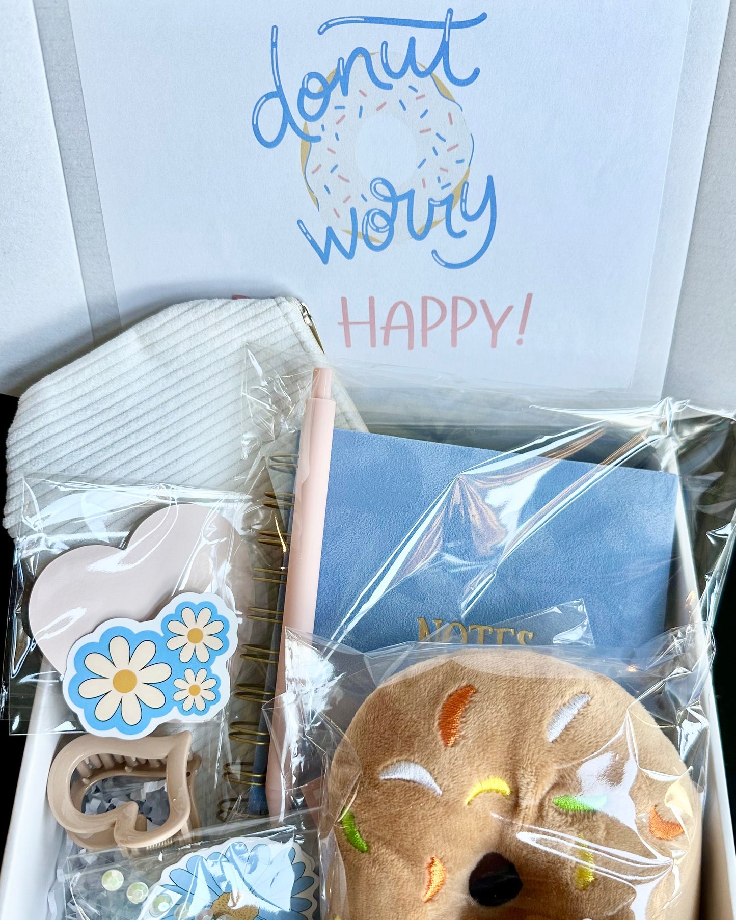 Gift box with a plush donut, card, and decorative items on a white background.