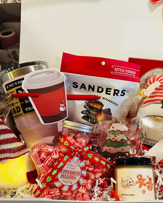 Holiday-themed gift box with candy, coffee, and decorative items on a table.