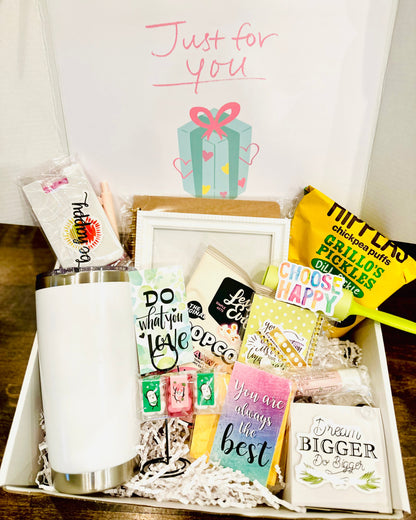 Gift basket with various items including a mug, cards, and a box on a wooden surface.