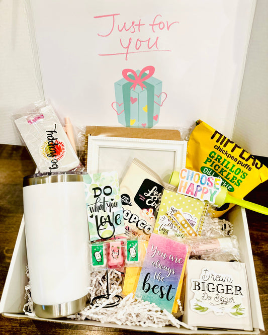 Gift basket with various items including a mug, cards, and a box on a wooden surface.