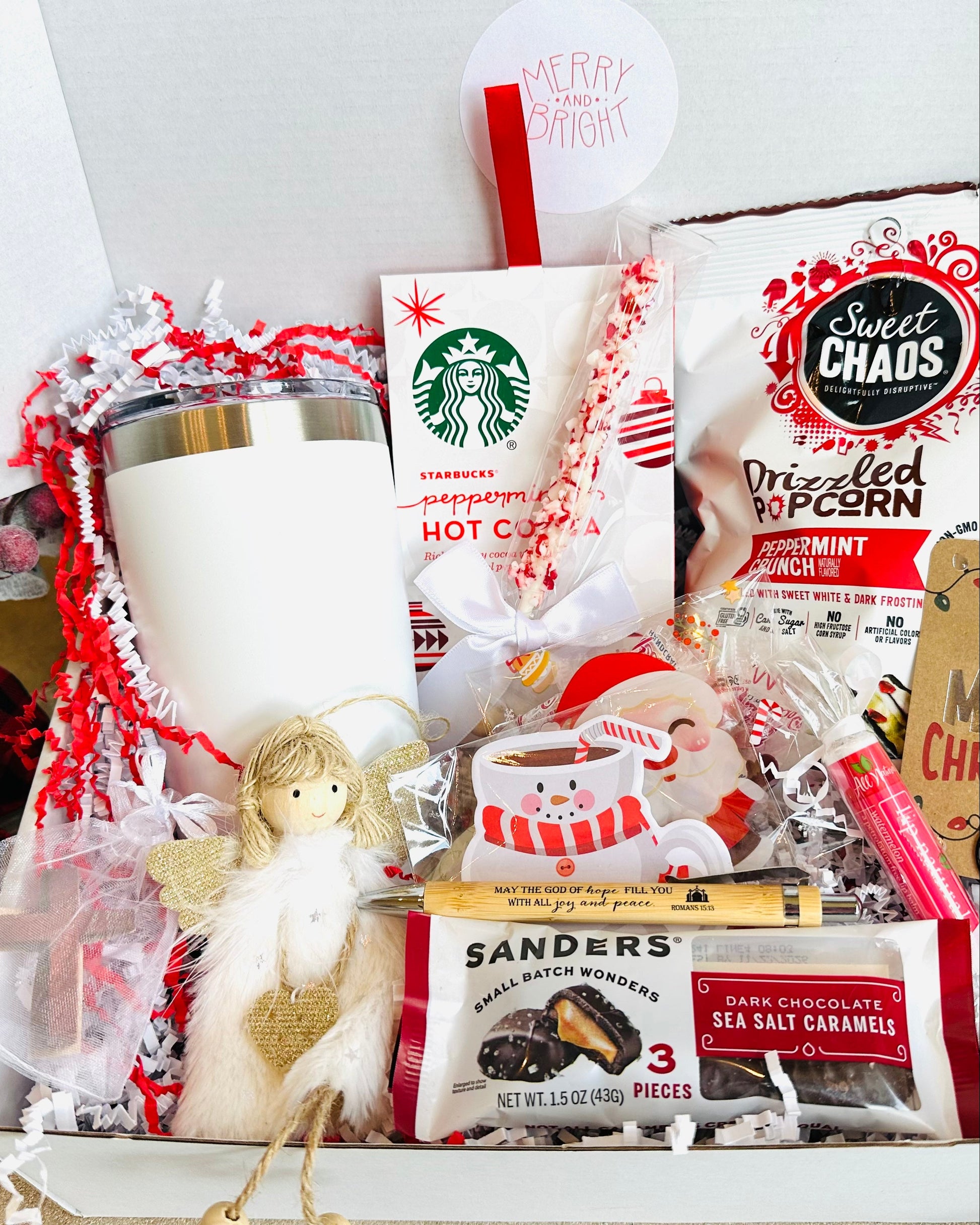 Gift basket with Starbucks hot cocoa packets, candy, and a mug on a white background