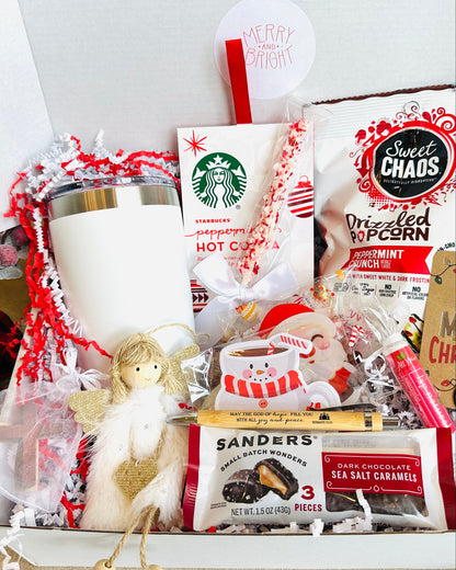 Gift basket with Starbucks hot cocoa packets, candy, and a mug on a white background