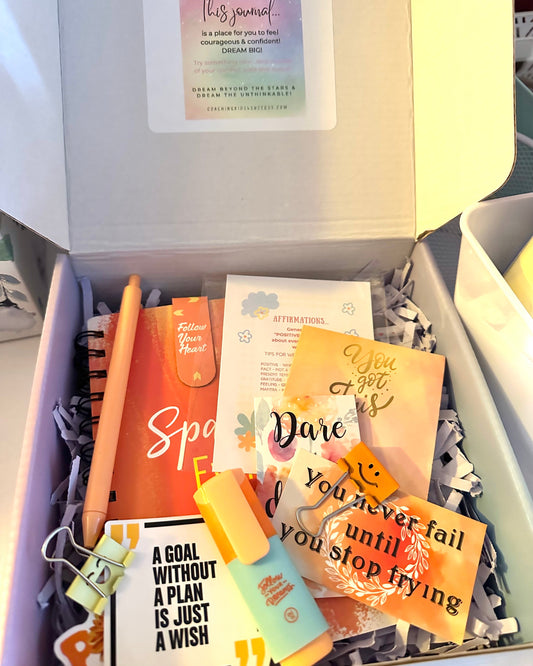 Gift box with motivational items including a pen, cards, and a notebook.