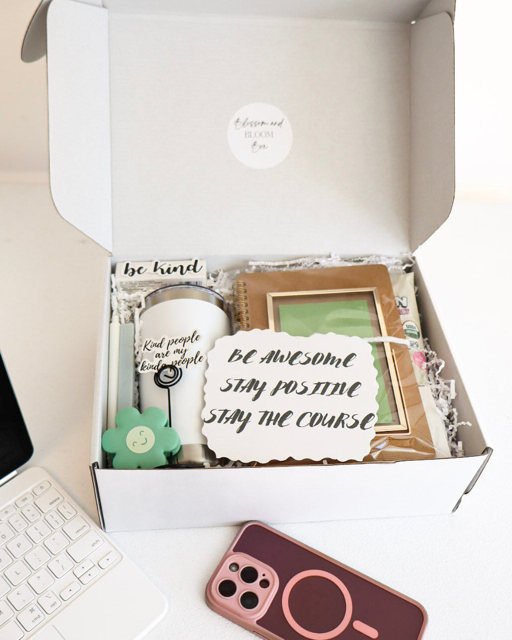 Open box containing decorative items with a laptop and phone on a desk.