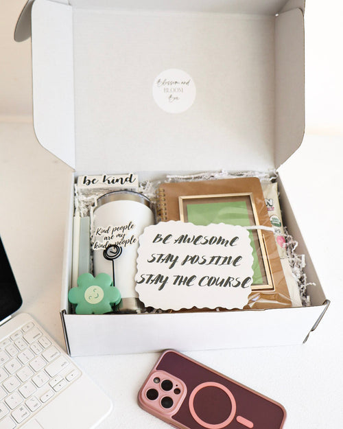Open box containing decorative items with a laptop and phone on a desk.