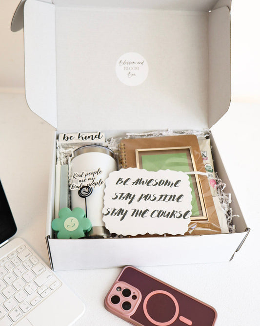 Open box containing decorative items with a laptop and phone on a desk.