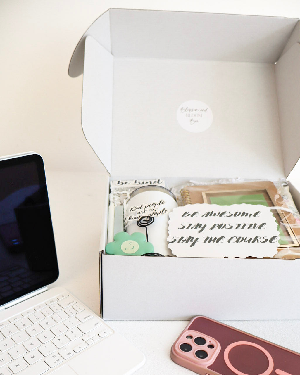 White box with decorative items on a desk next to a laptop and phone