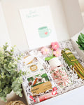 Gift box with tea bags, a mug, and decorative items on a white background