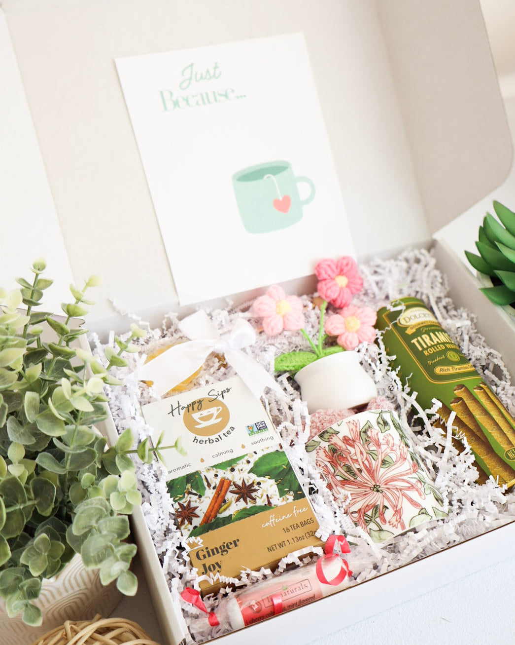 Gift box with tea bags, a mug, and decorative items on a white background
