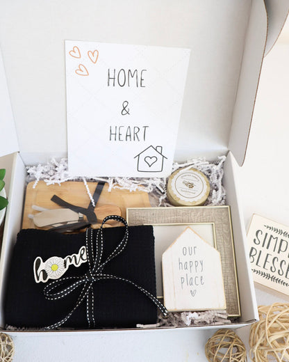 Gift box with decorative items including a black bag with 'home' text, a small clock, and cards.
