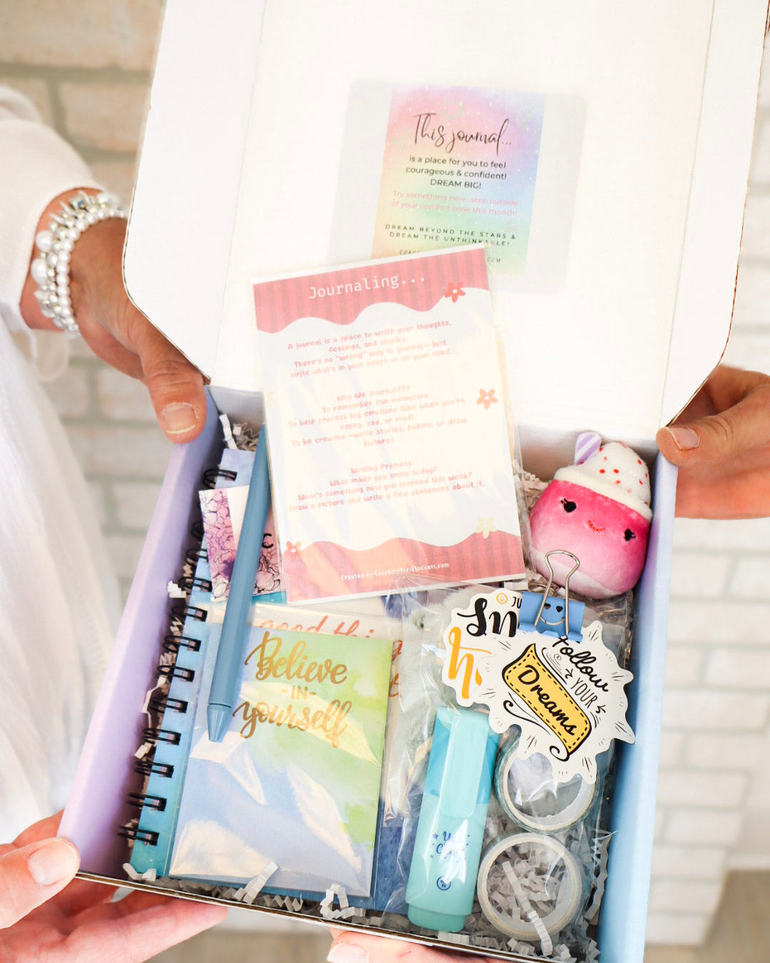 Gift set with a notebook, stationery items, and a plush toy in a box.