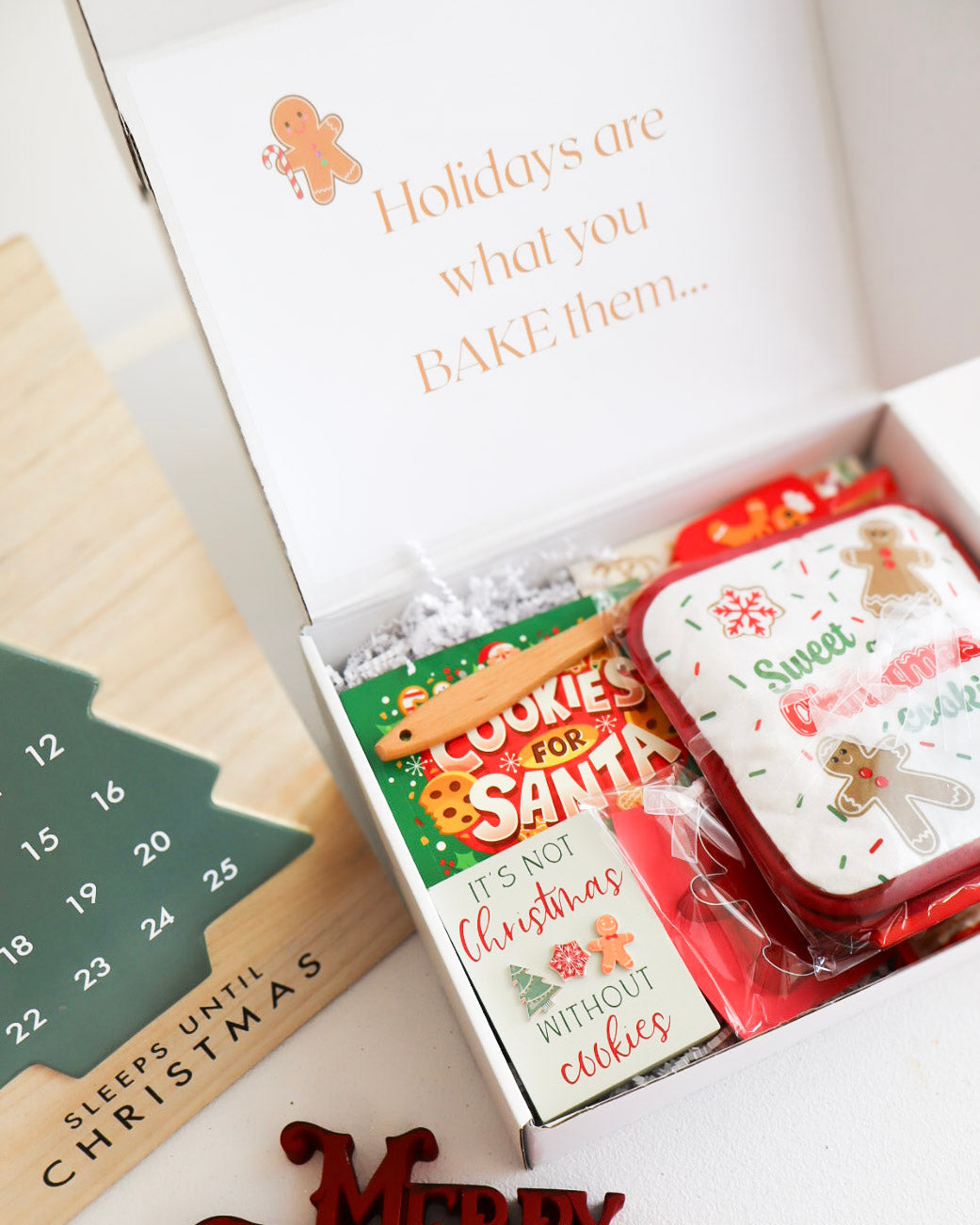 Christmas-themed cookie tins in a box with a 'Merry Christmas' decoration and a countdown calendar.